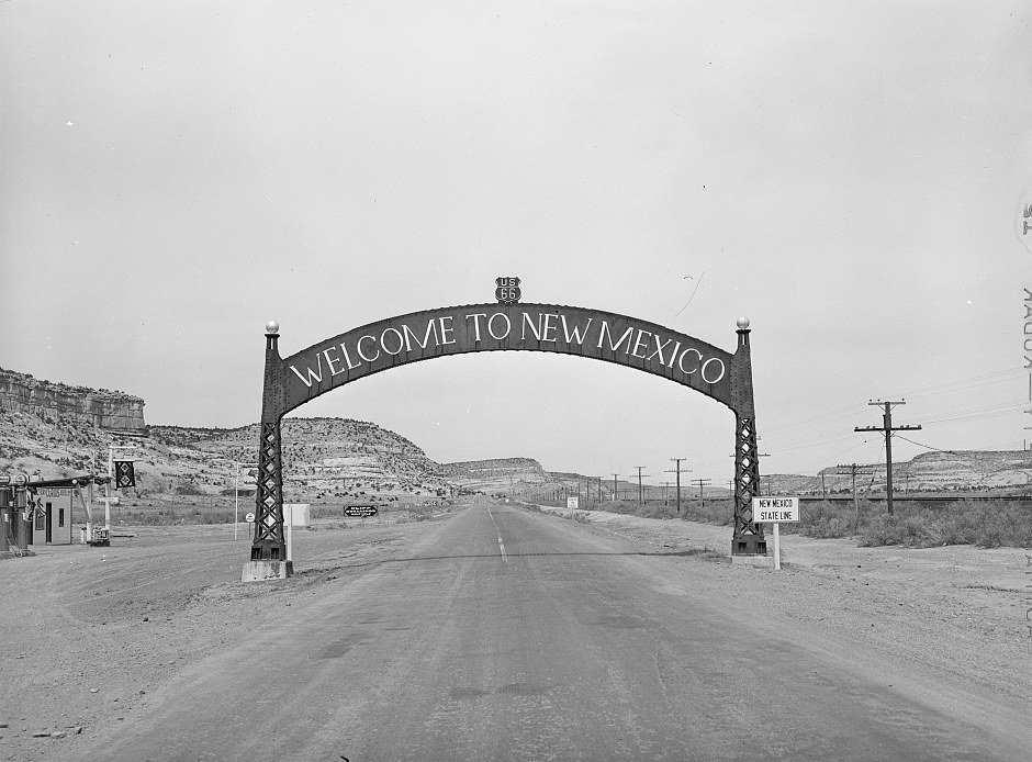 Black-and-white 1940 photo of a Welcome to New Mexico arch over U.S. Route 66 at the Arizona state line