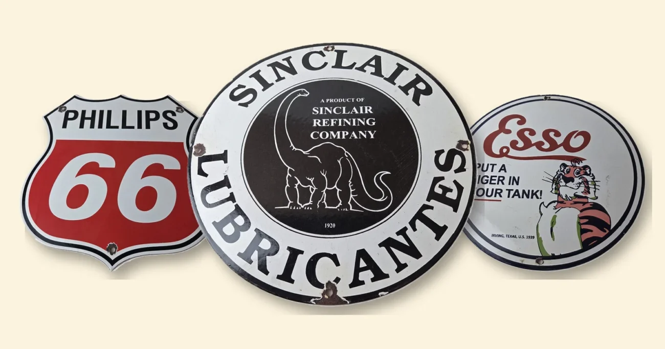 Sinclair dinosaur logo on a round Sinclair Lubricantes porcelain sign, between Phillips 66 and Esso tiger signs