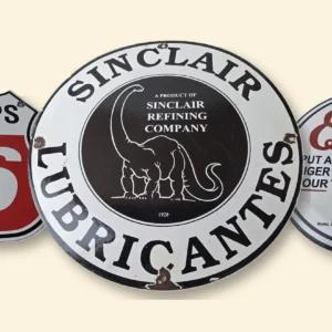 Sinclair dinosaur logo on a round Sinclair Lubricantes porcelain sign, between Phillips 66 and Esso tiger signs